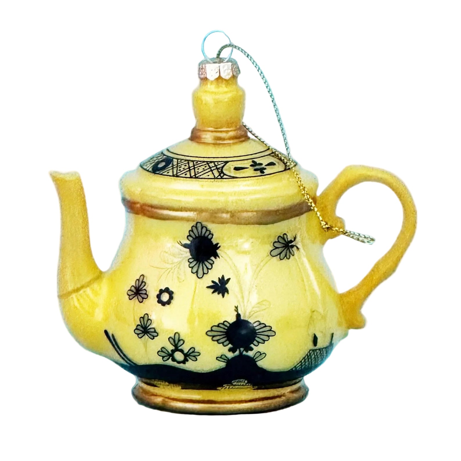 A decorative yellow teapot-shaped ornament with black floral and bee motifs, a gold-colored hanging loop, and a gold top finial, shown against a solid light blue background.