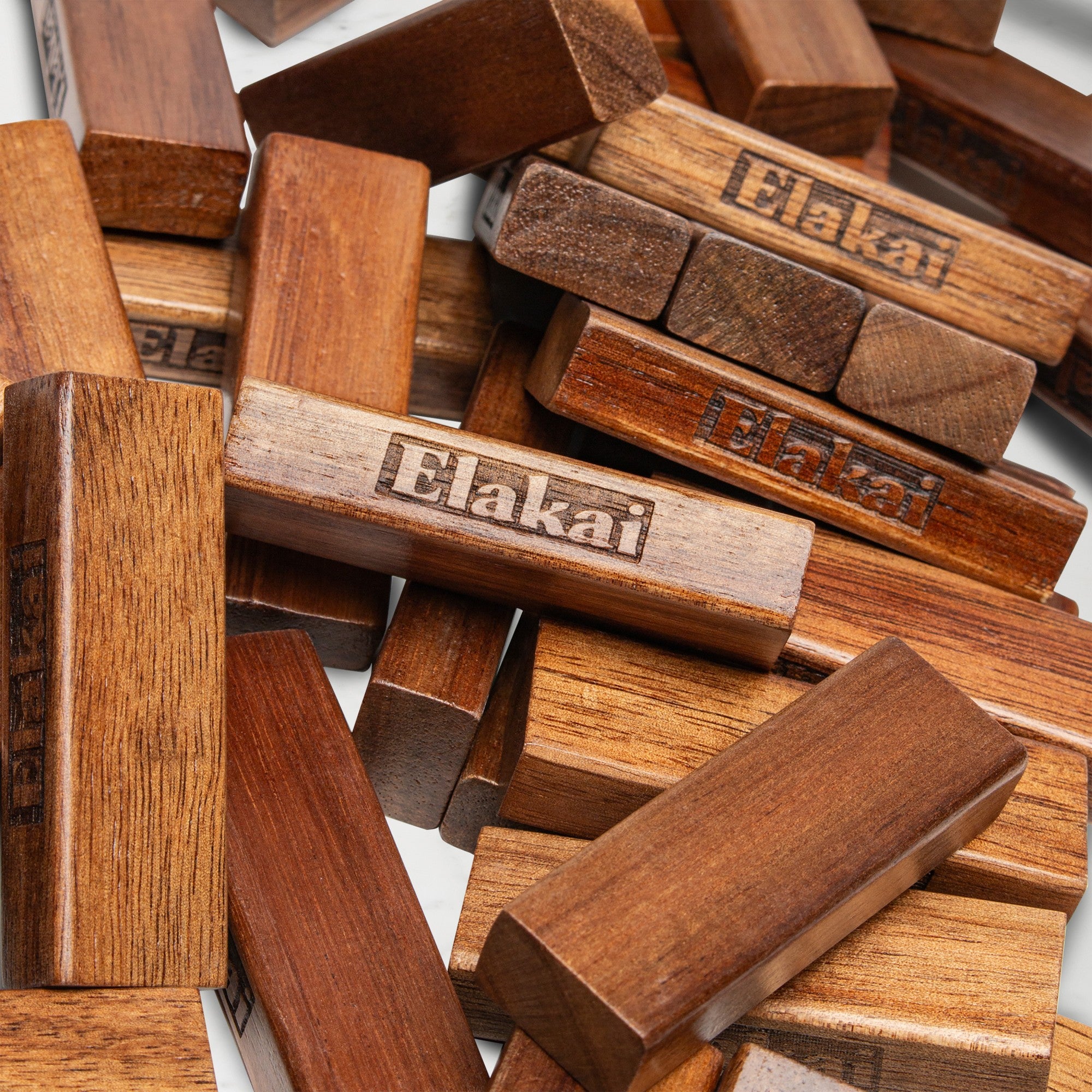 Jenga Elakai blocks with 'Elakai' branding scattered on a white surface