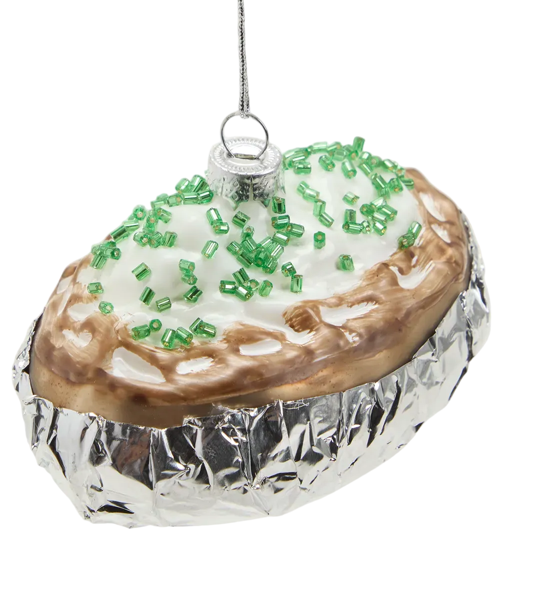 Decorative glass ornament shaped like a pie with green sprinkles on a white background