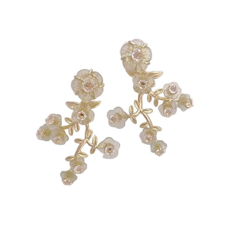 A pair of gold floral branch earrings with small translucent pale green flower petals and clear rhinestone centers, displayed on a clean white background.