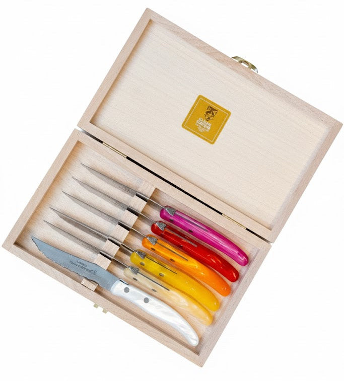 Set of colorful knives in a wooden box on a white background