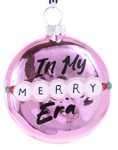 Pink ornament with 'In My Merry Era' text and 'Swiftie' hanging above on a white background