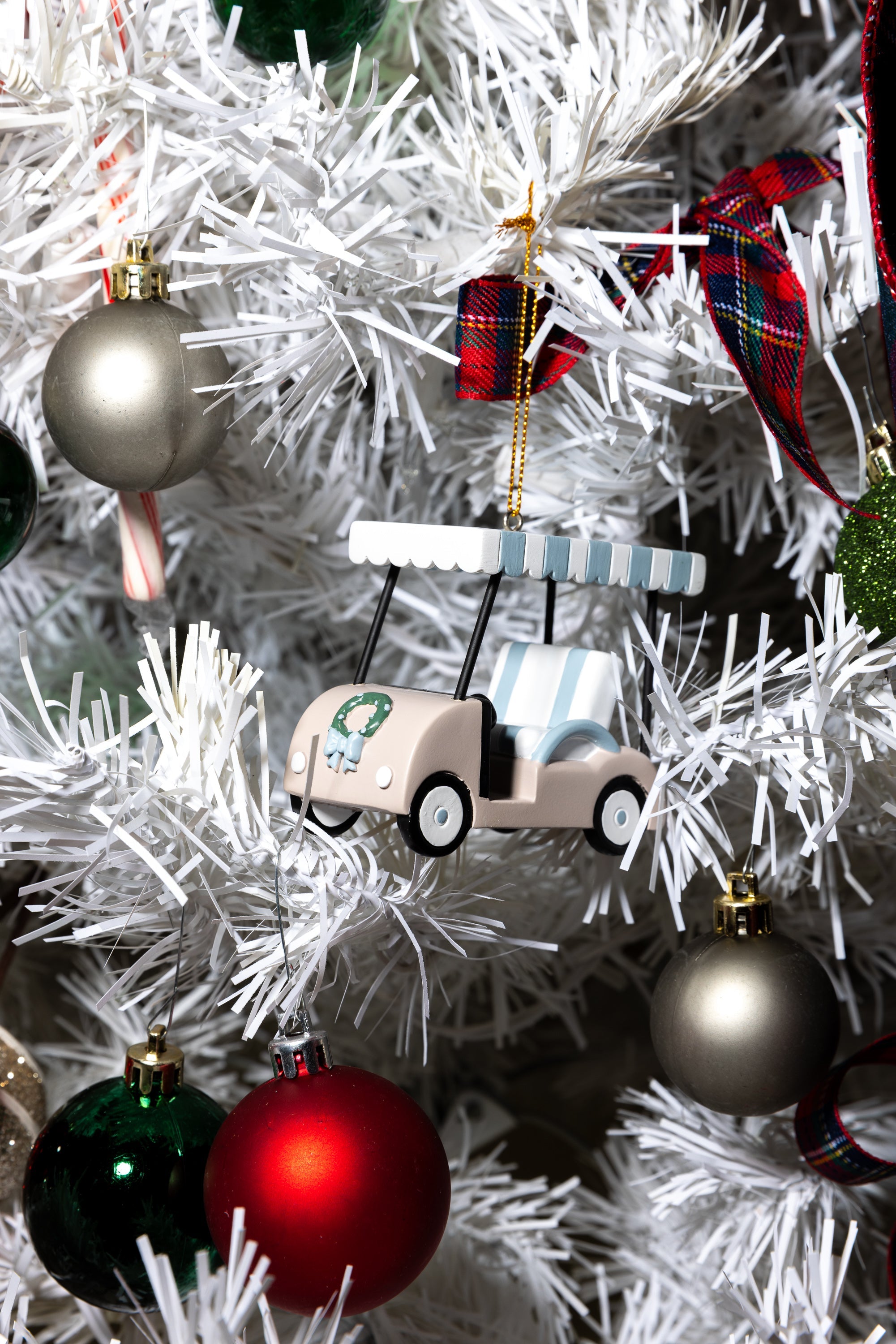 Decorative golf cart ornament on a Christmas tree with colorful ornaments.