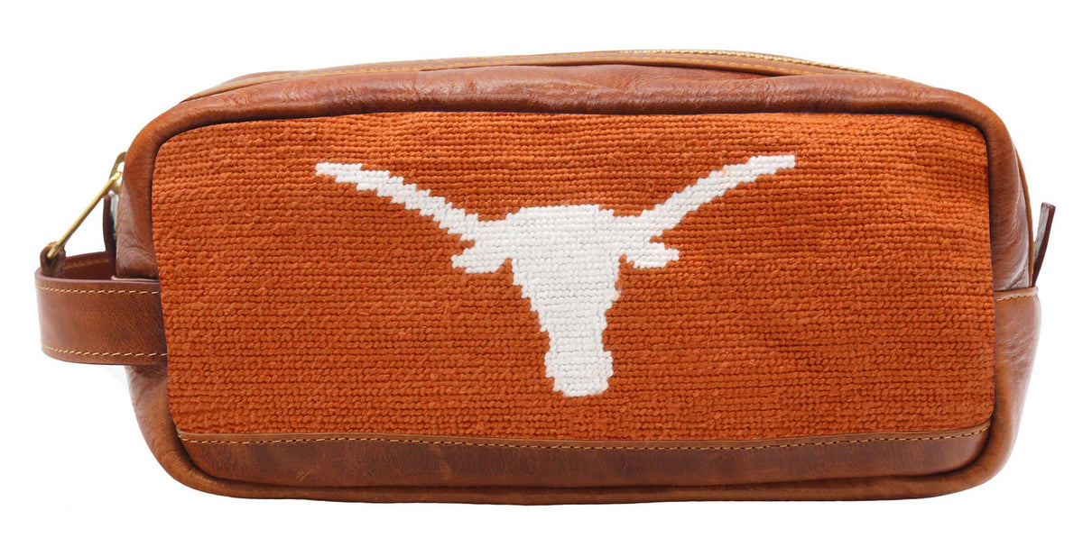 Brown leather and needlepoint bag with a white logo on a white background