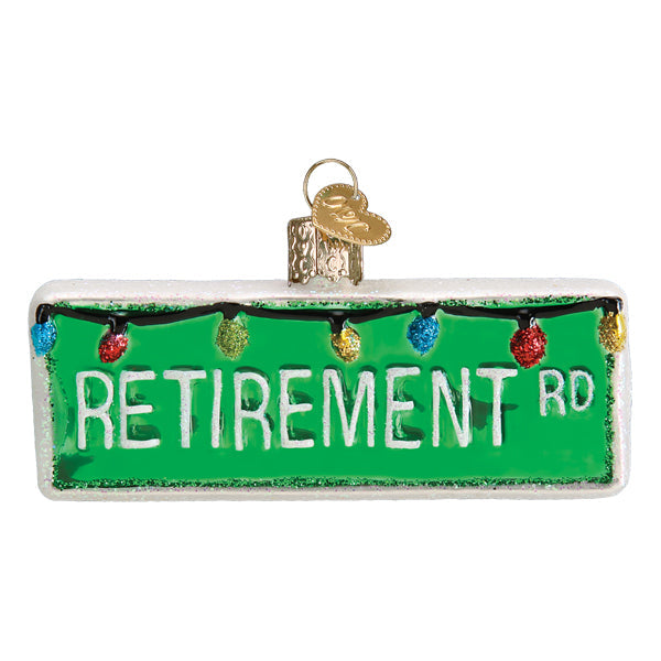 Decorative ornament shaped like a street sign with 'RETIREMENT RD' text and Christmas lights.