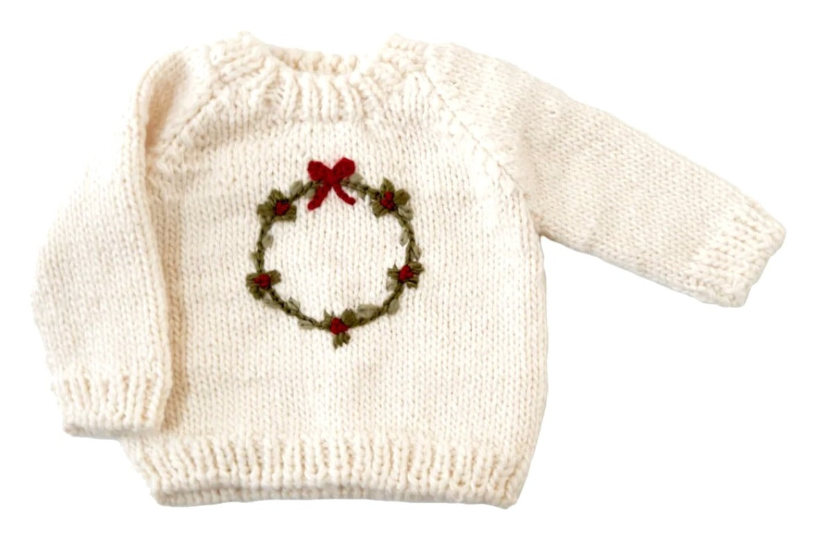 White sweater with a Christmas wreath design on a white background