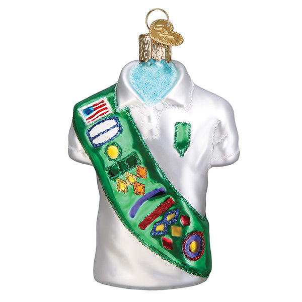 Glass ornament of a girl scout uniform with a sash on a white background