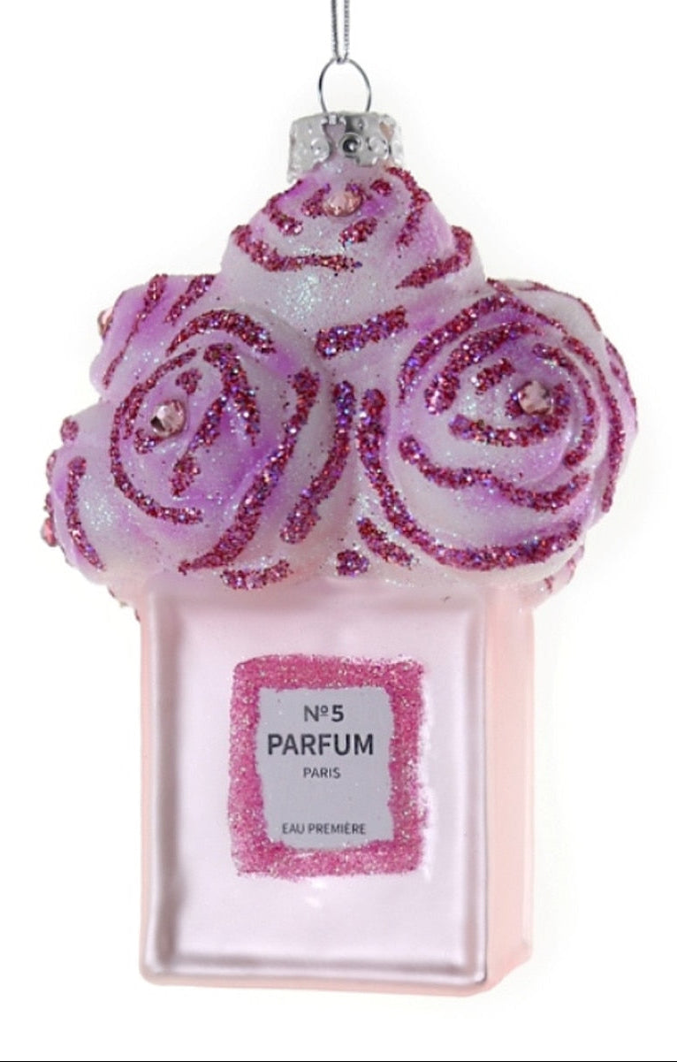 Decorative ornament shaped like a pink perfume bottle with purple floral design on a white background