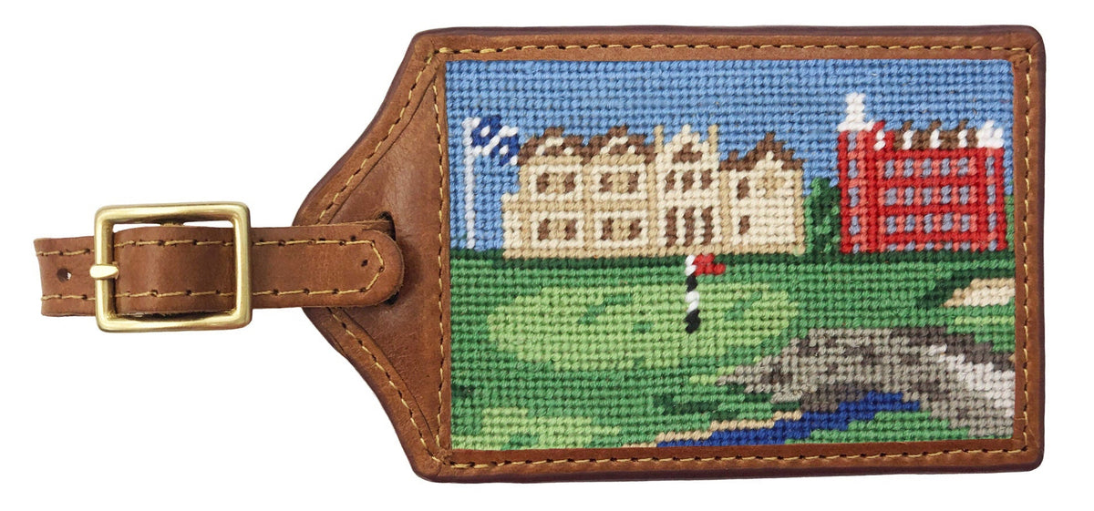 Luggage tag with needlepoint design of a golf course and clubhouse on a white background