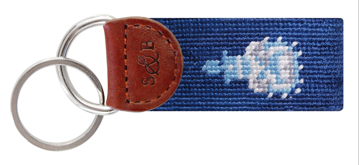 Keychain with blue needlepoint design and brown leather strap on a white background