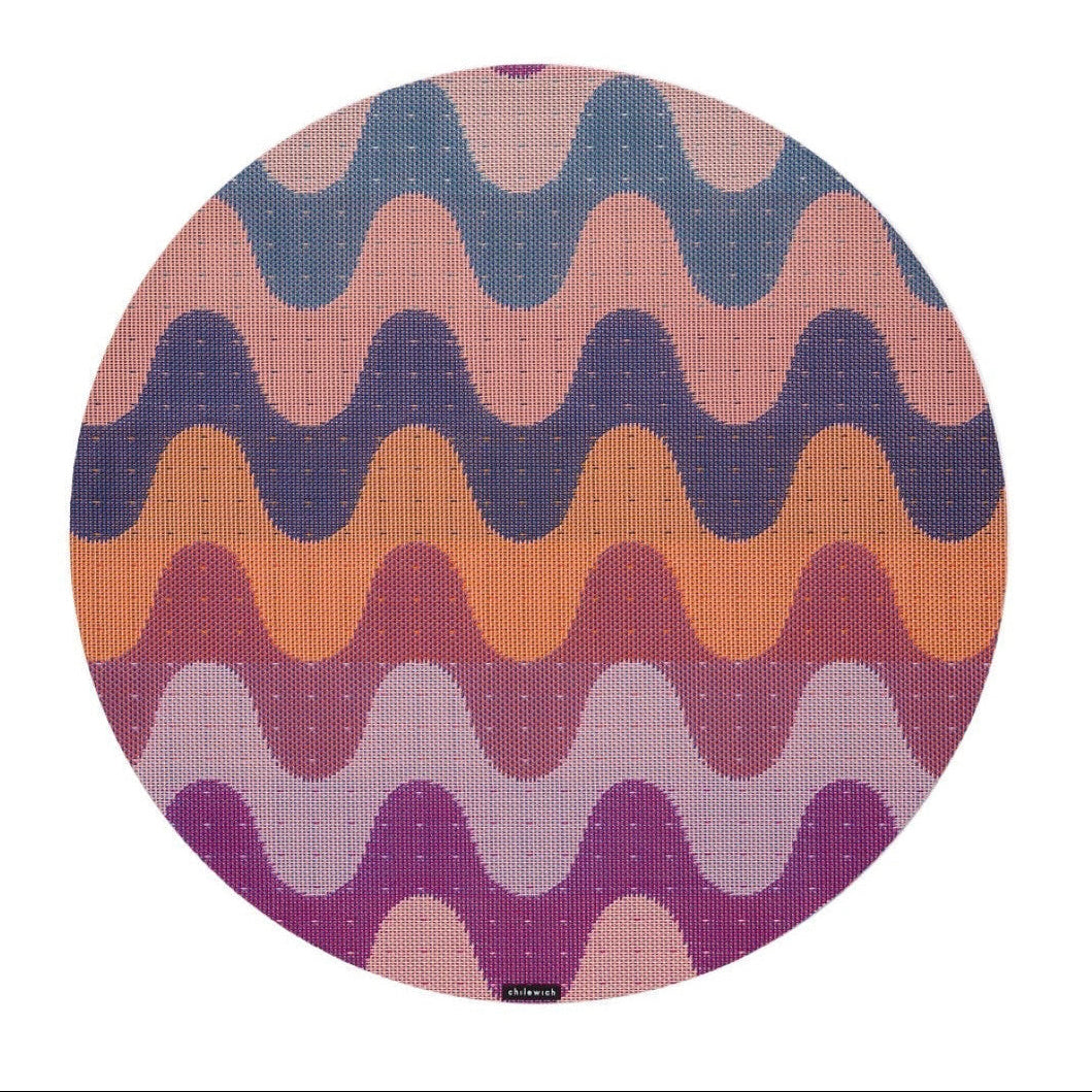 Round mat with wavy pattern in purple, orange, and pink on a white background