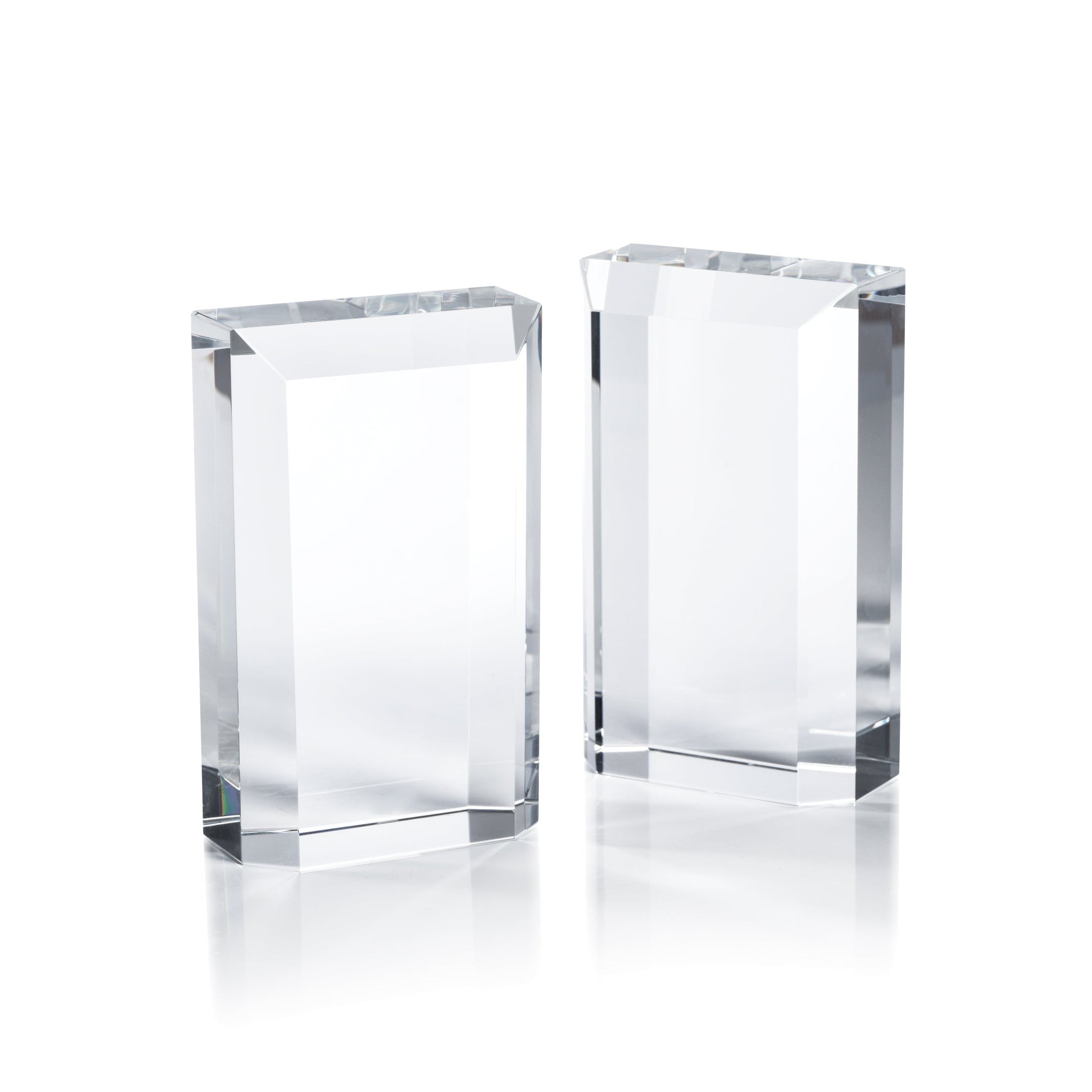 Two clear glass bookends on a white background