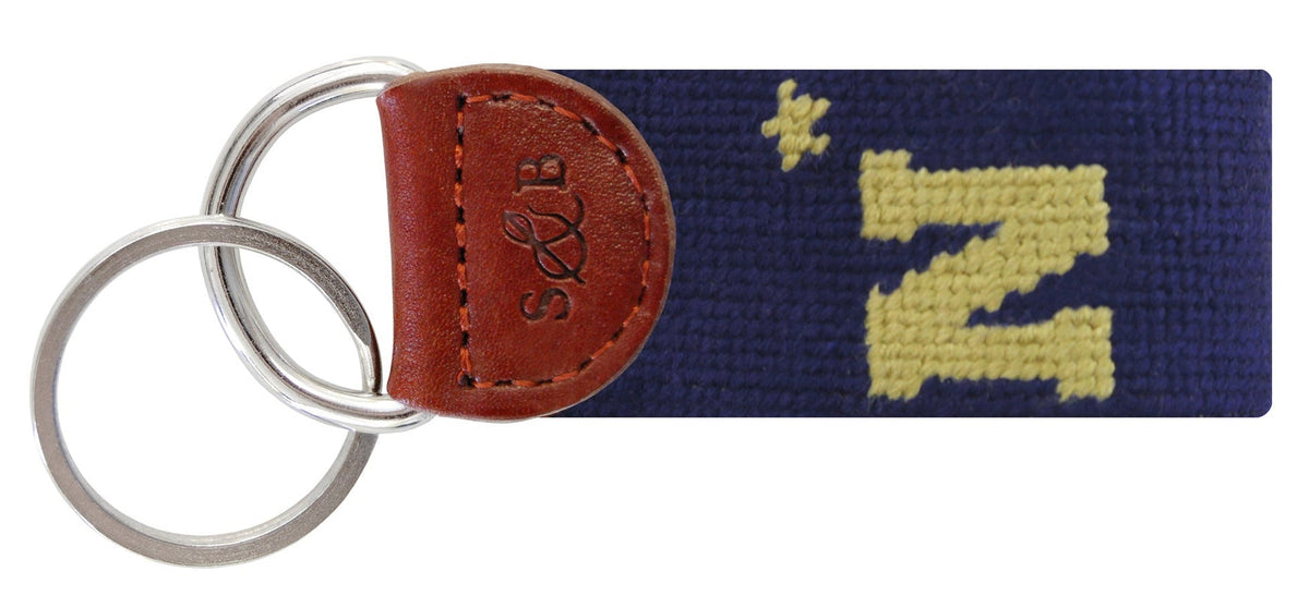 Keychain with navy strap featuring a yellow 'N' and brown leather tab on a white background