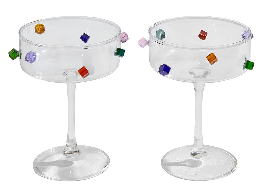 Two clear cocktail glasses with colorful gemstones on a white background