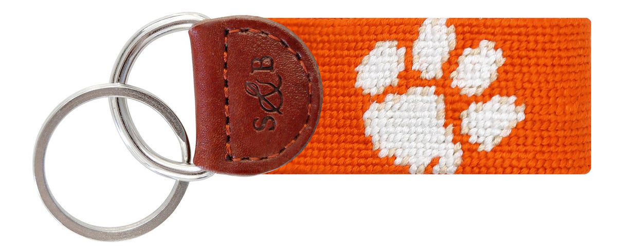 Keychain with orange strap featuring a white paw print design on a white background