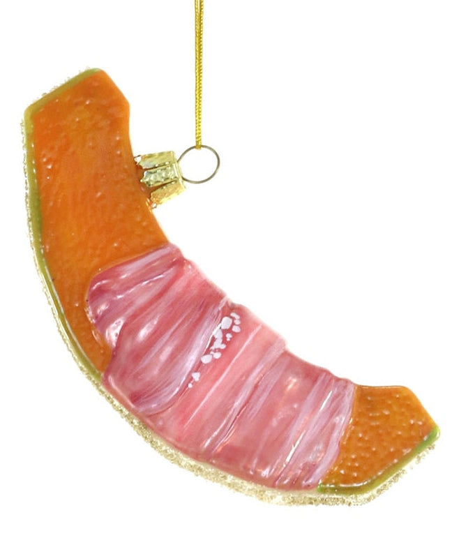 A novelty Christmas ornament shaped like a sliced peach, featuring a textured orange-pink flesh with a gold glittery edge and a gold hanging loop at the top, shown against a plain white background.