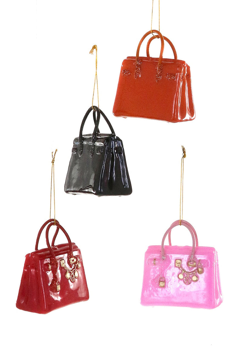 Five shiny handbags in different colors hanging against a white background