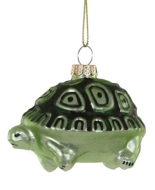 A green glass turtle ornament with a gold hanging string, shown against a plain white background.
