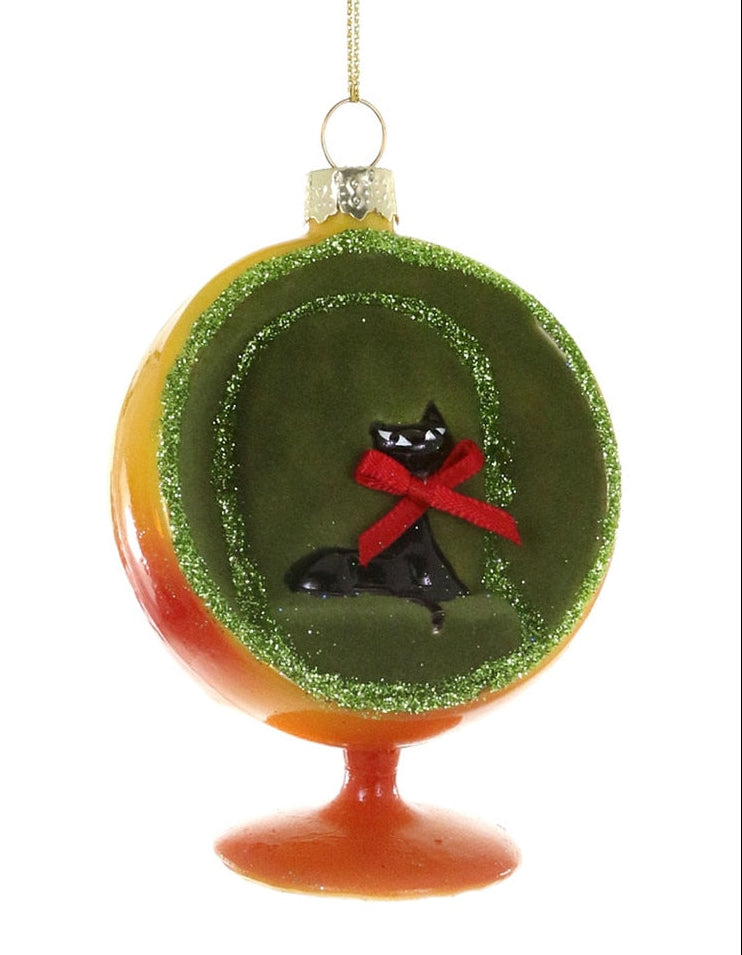 A round glass Christmas ornament featuring a black cat wearing a red bow tie inside a green glittery circular frame, with a yellow-to-orange gradient outer border and a red-orange base, hanging against a white background.