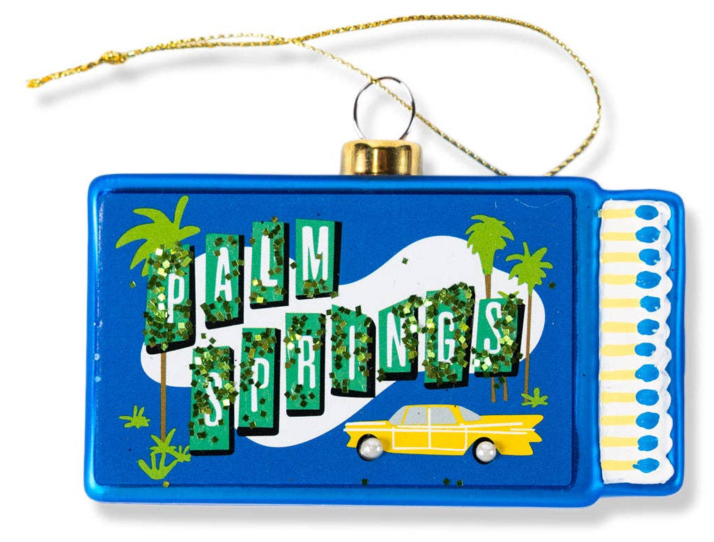 Decorative ornament with 'Palm Springs' text and palm trees on a blue background.