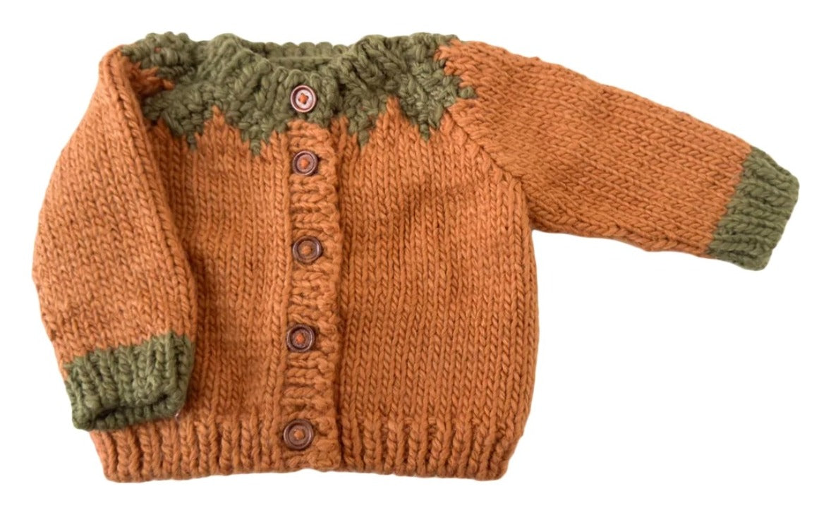 A hand-knit baby cardigan sweater in rust orange with an olive green yoke and matching green ribbed cuffs and hem, featuring brown buttons down the front.