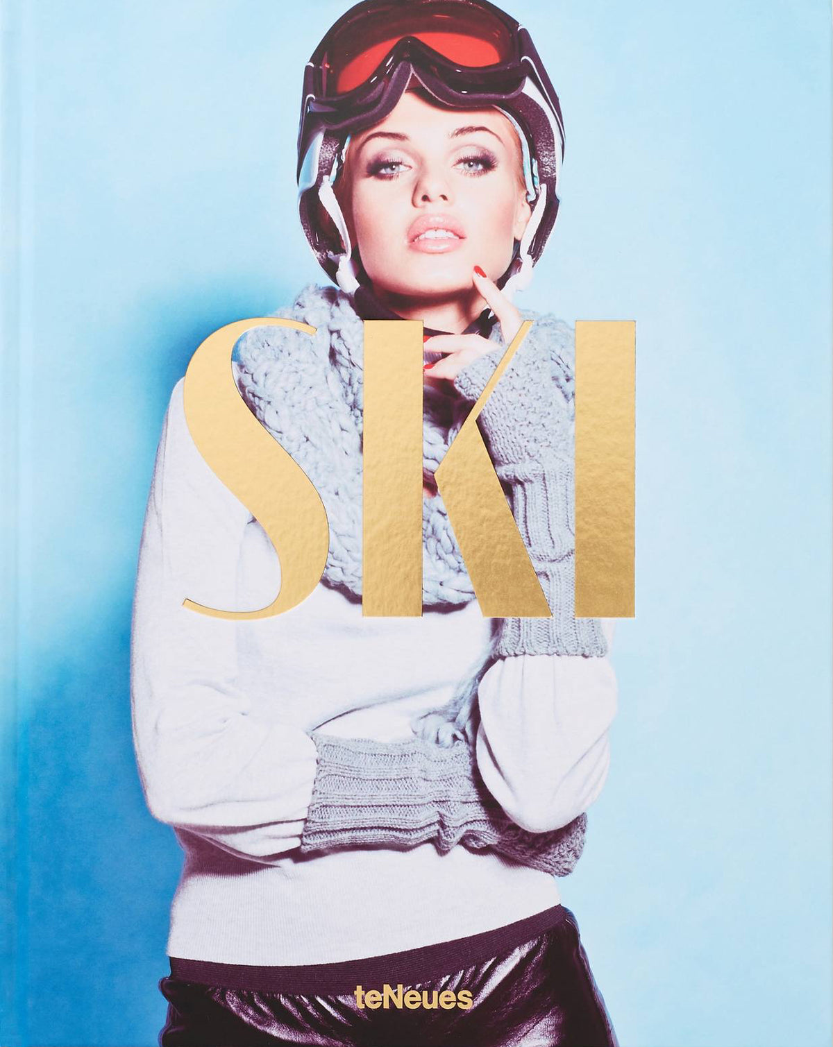 A hardcover book titled 'SKI' by leNeues, featuring a cover photograph of a woman in ski gear against a light blue background with a large gold foil 'SKI' overlay.