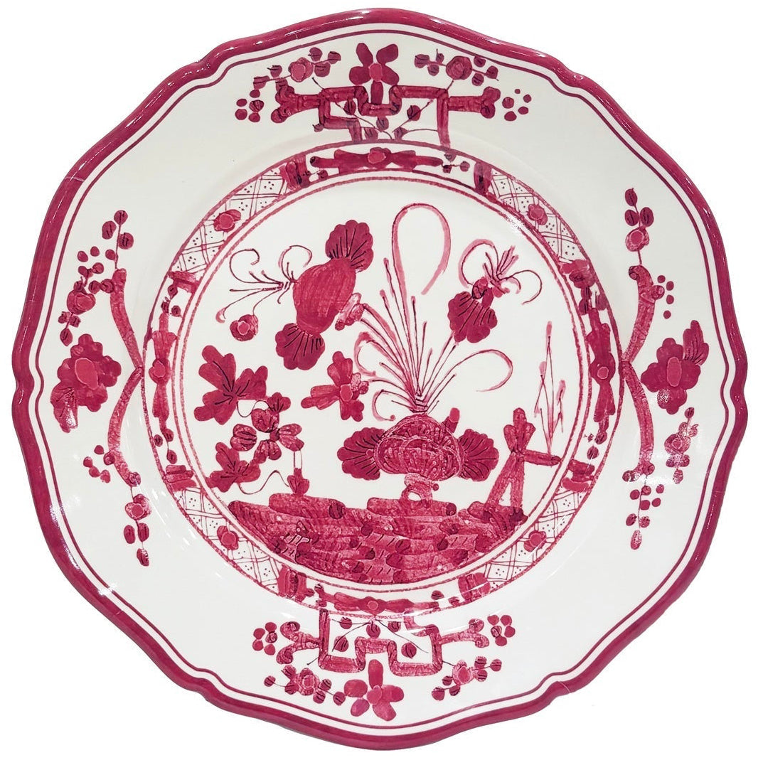 Decorative plate with red floral and landscape design on a white background