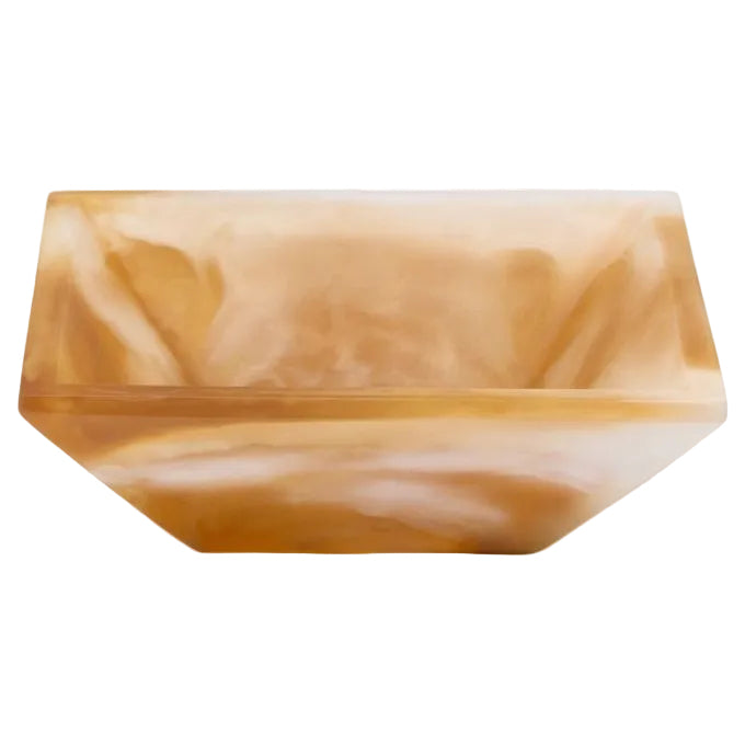 A square resin bowl with a marbled amber, tan, and cream pattern, photographed on a clean white background.