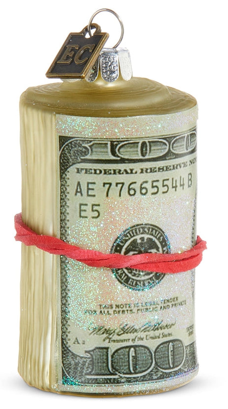 Decorative ornament shaped like a roll of money with a red rubber band on a white background