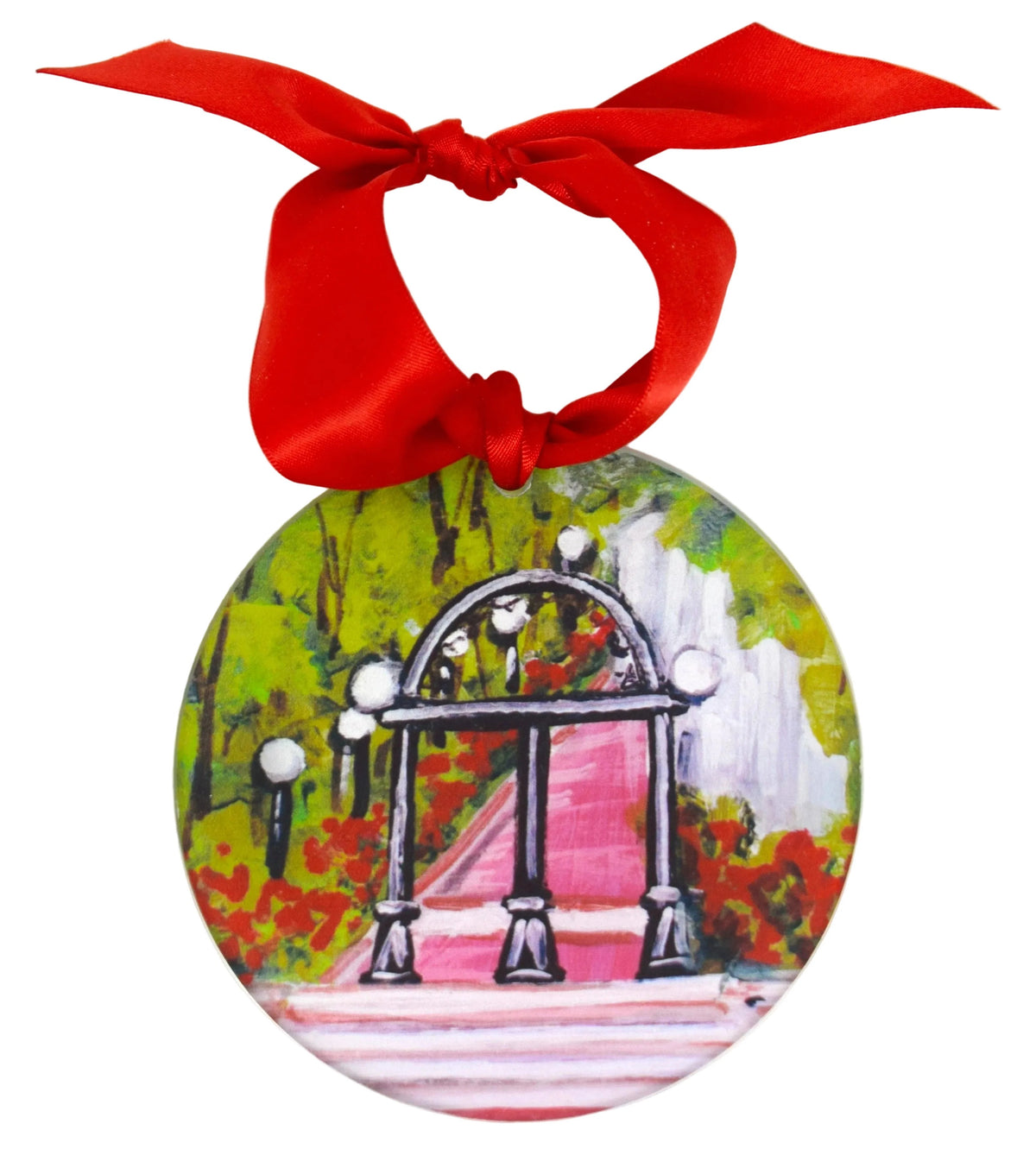 A round hanging ornament featuring a painted scene of an arched walkway with a pink path, green foliage, and white lamp posts, suspended from a bright red ribbon bow against a plain white background. University of Georgia ornament