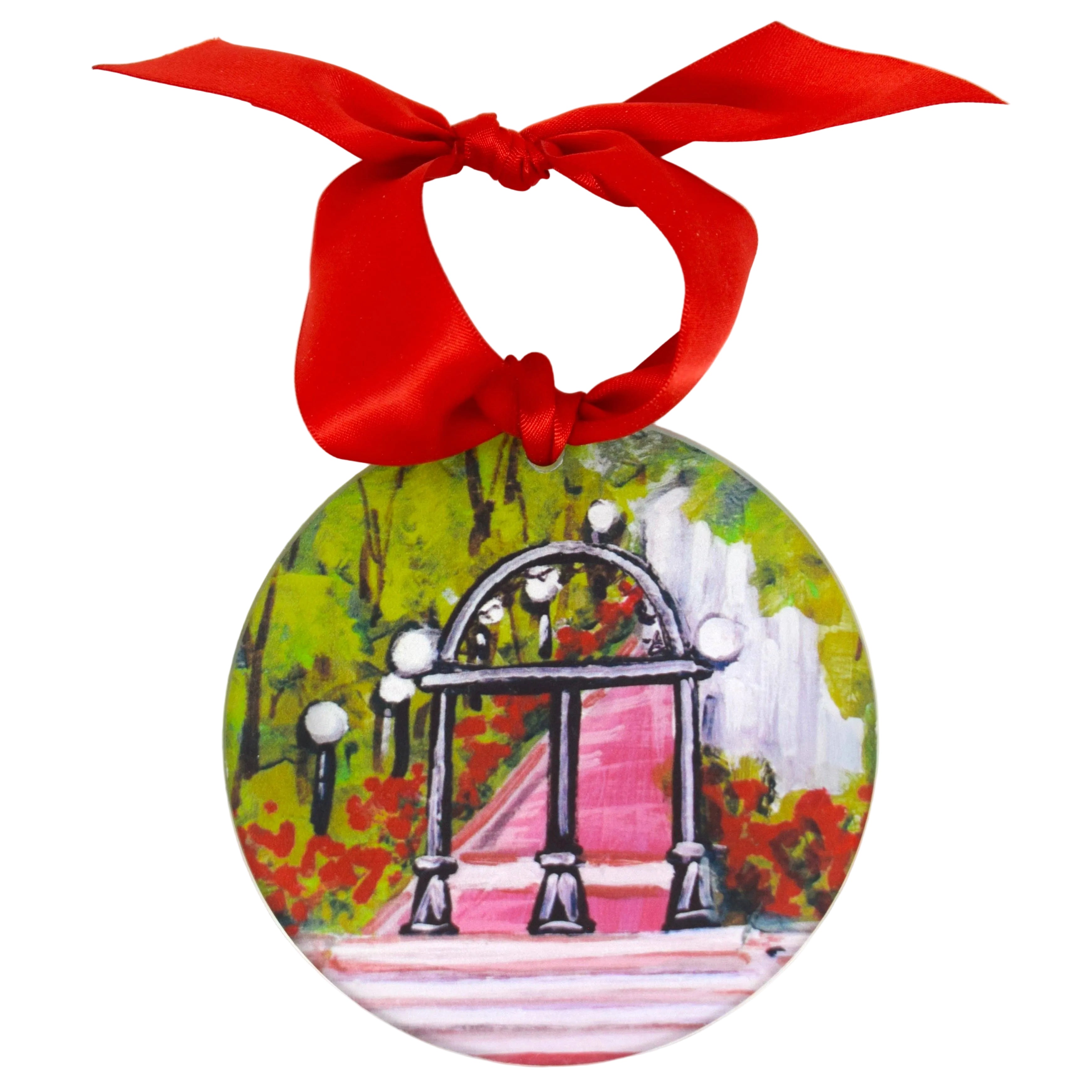A round hanging ornament featuring a painted scene of an arched walkway with a pink path, green foliage, and white lamp posts, suspended from a bright red ribbon bow against a plain white background. University of Georgia ornament