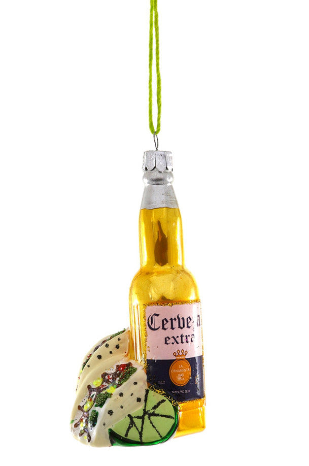 A glass ornament designed to look like a beer bottle with a taco inside, featuring a label and a green cap.