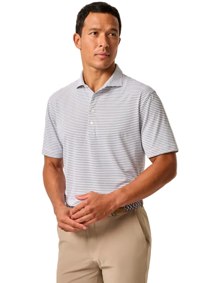 A man wearing a short-sleeve polo shirt with thin navy and white horizontal stripes, paired with khaki pants, standing against a plain beige studio background.
