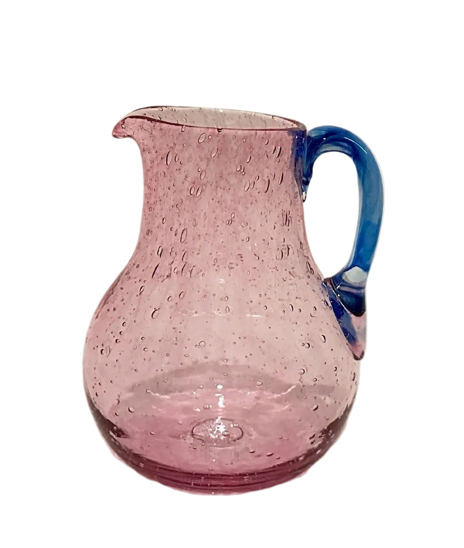 Pink glass pitcher with blue handle on a white background