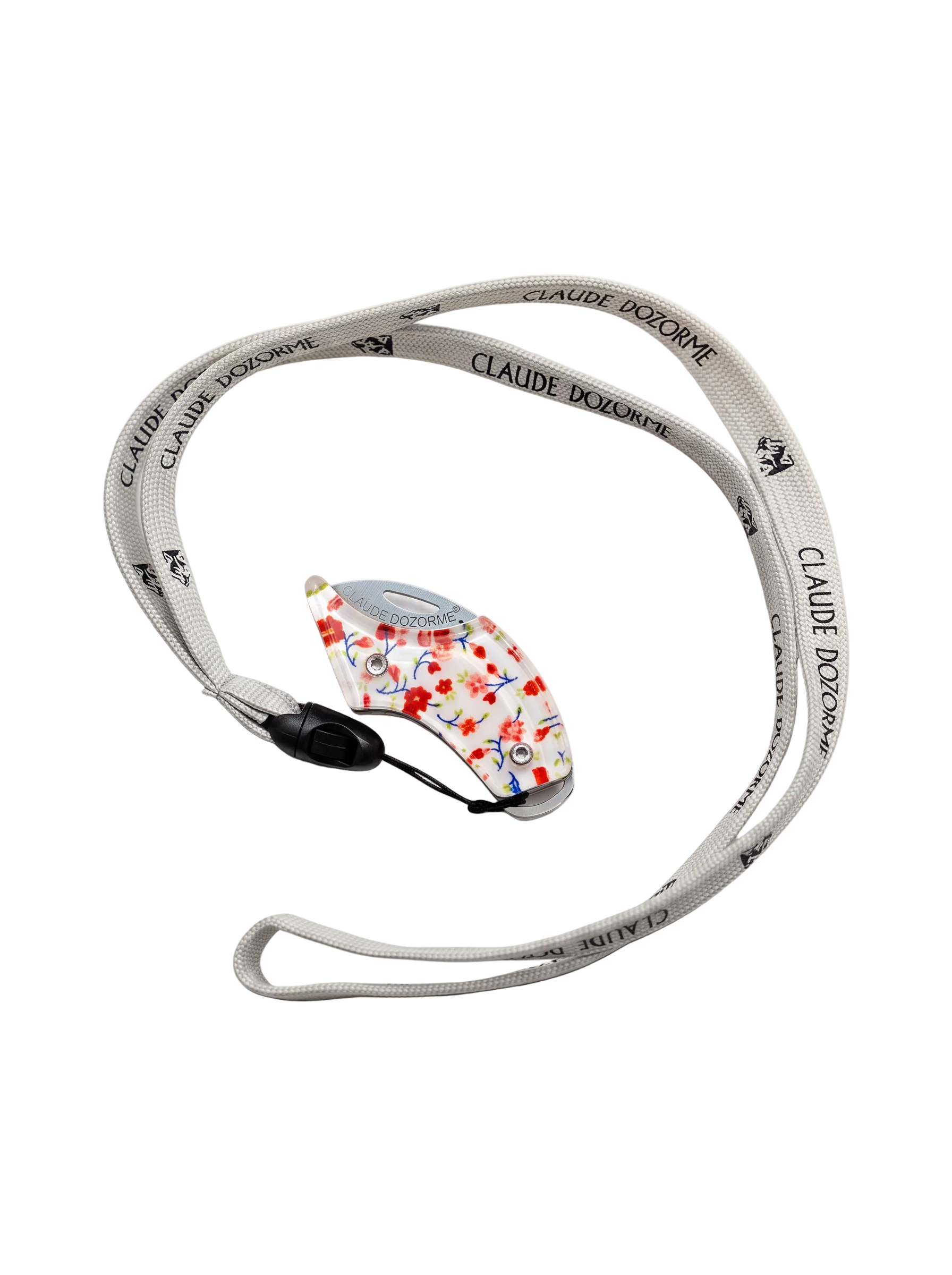A light gray fabric wrist strap with black 'CLAUDIE DOZORME' branding connected to a floral pattern knife, on a clean white background.