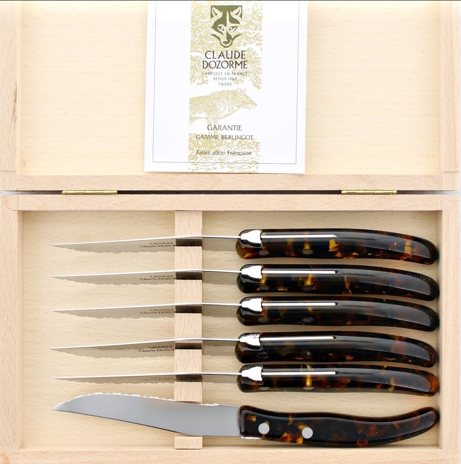 Set of knives with tortoiseshell handles in a wooden box, featuring the brand 'Claude Dozorme'.