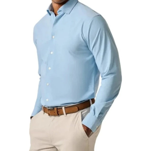 Man wearing a light blue dress shirt and beige pants against a plain background