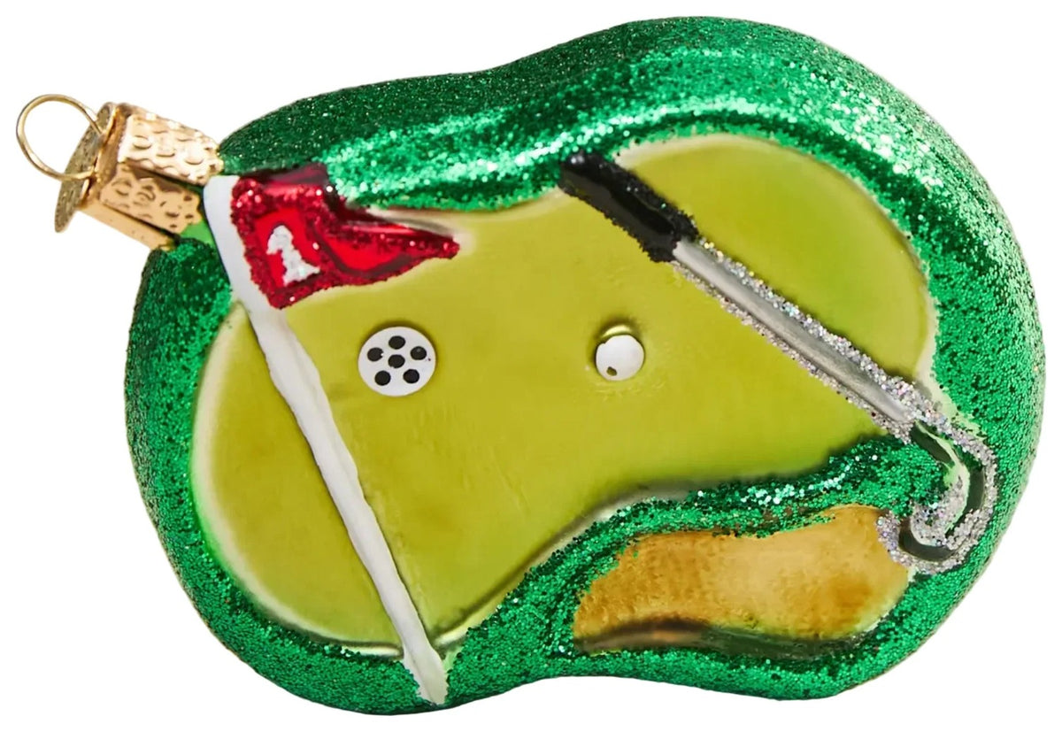 Golf ornament with green glitter, white ball, and red flag on a beige background