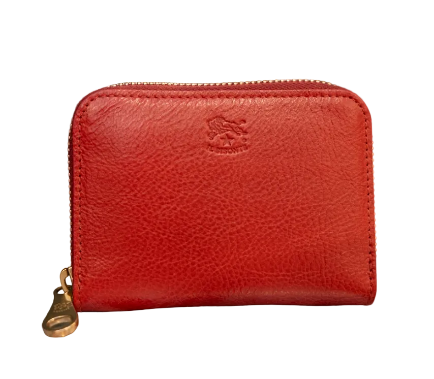 A red textured italian leather zip-around wallet with a gold-tone zipper and a debossed logo on the front, resting on a patterned surface against a dark green background with white polka dots.