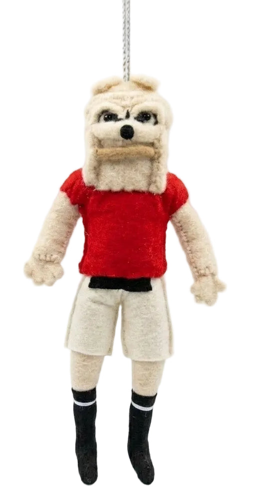A small plush hanging doll or ornament shaped like a dog-like character wearing a red shirt, cream shorts, black socks, and a cream face mask, suspended against a plain white background.