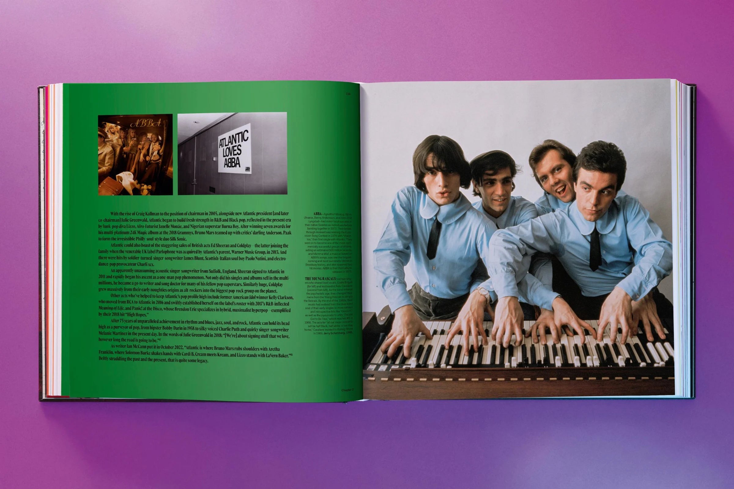 Open book showing a page with a green background and text, and another page with a photo of four men playing keyboard.