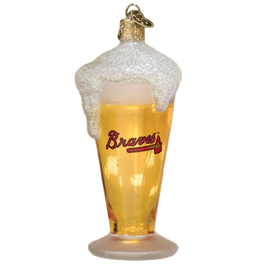A glass of beer ornament with Atlanta Braves branding, hanging on a Christmas tree with holly and lights in the background.