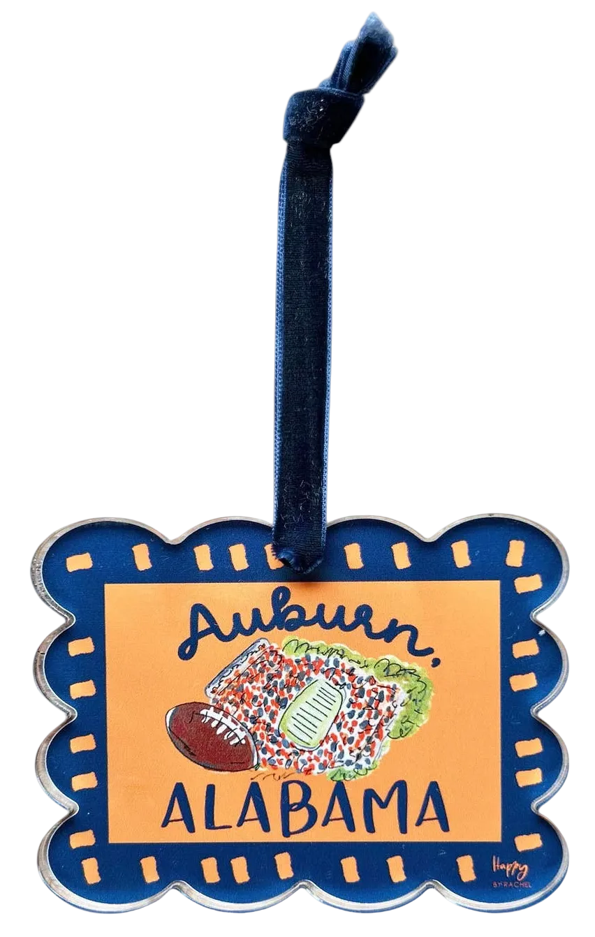 Miller Collective Auburn acrylic scallop stadium ornament with a navy velvet ribbon on a rustic wooden background.