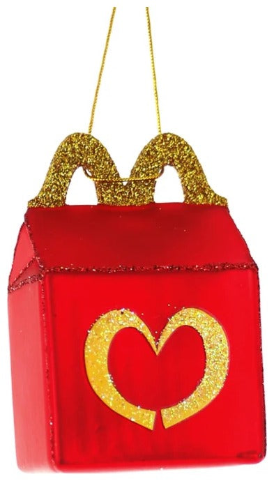 A red and gold glittery glass ornament designed to resemble a McDonald's happy meal box with a heart-shaped detail.