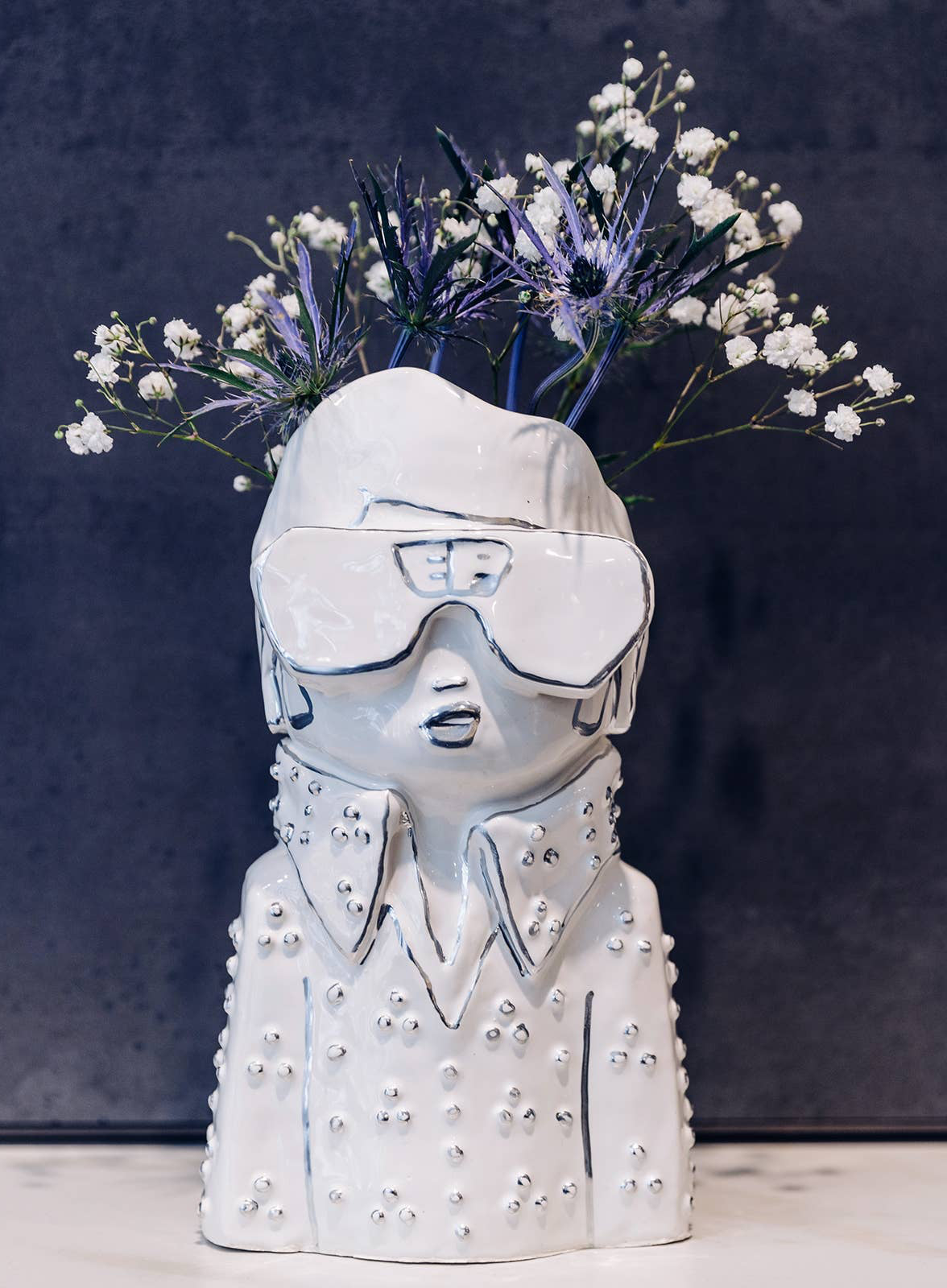 Vase shaped like a person with flowers on a dark background