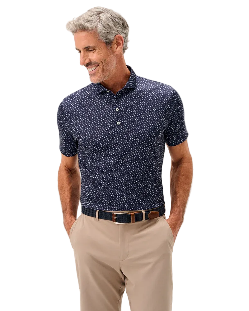 Man wearing a navy polo shirt with a subtle pattern and beige pants on a light gray background