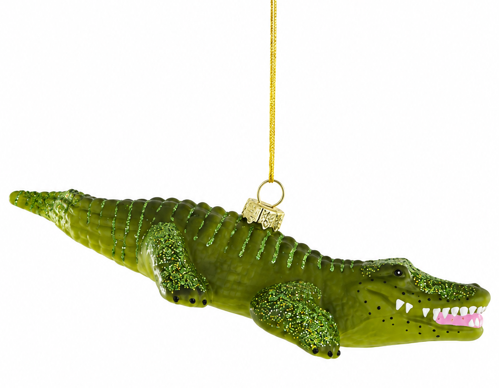 A green glittery crocodile ornament with an open mouth showing white teeth, suspended by a gold string against a plain white background.
