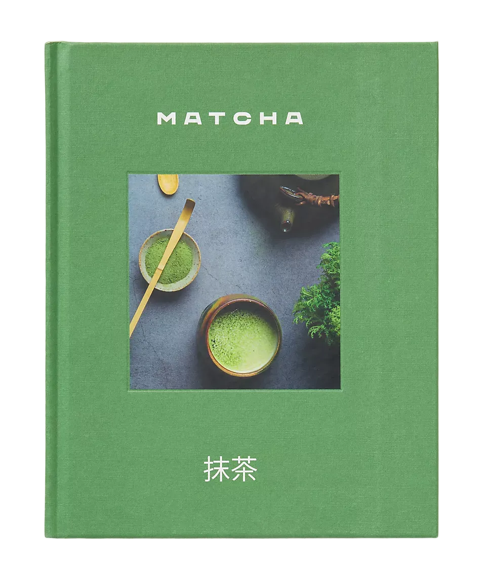 A hardcover book titled 'MATCHA' with Japanese characters below, featuring a green cover and a central square photograph of matcha tea bowls on a dark surface, set against a light beige background.