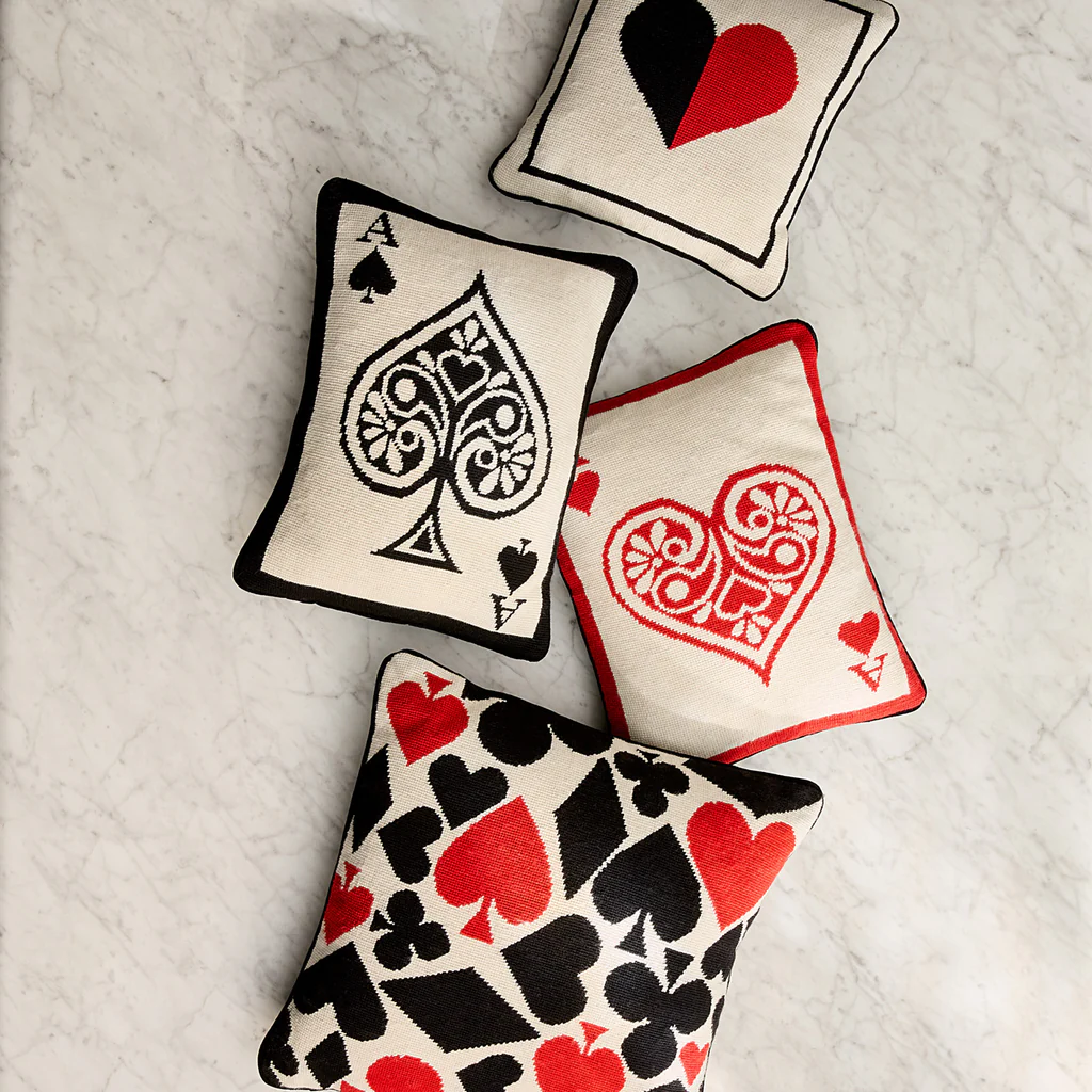 Four decorative pillows with playing card symbols on a textured surface