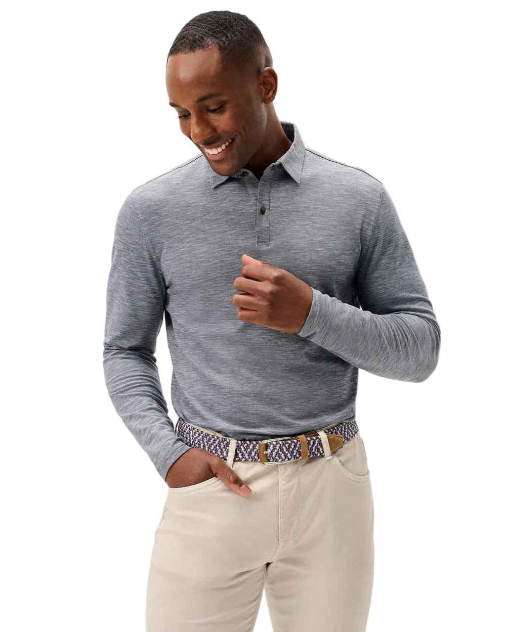 A man wearing a heather gray long-sleeve polo shirt, cream-colored pants, and a patterned belt, standing against a light gray studio background.